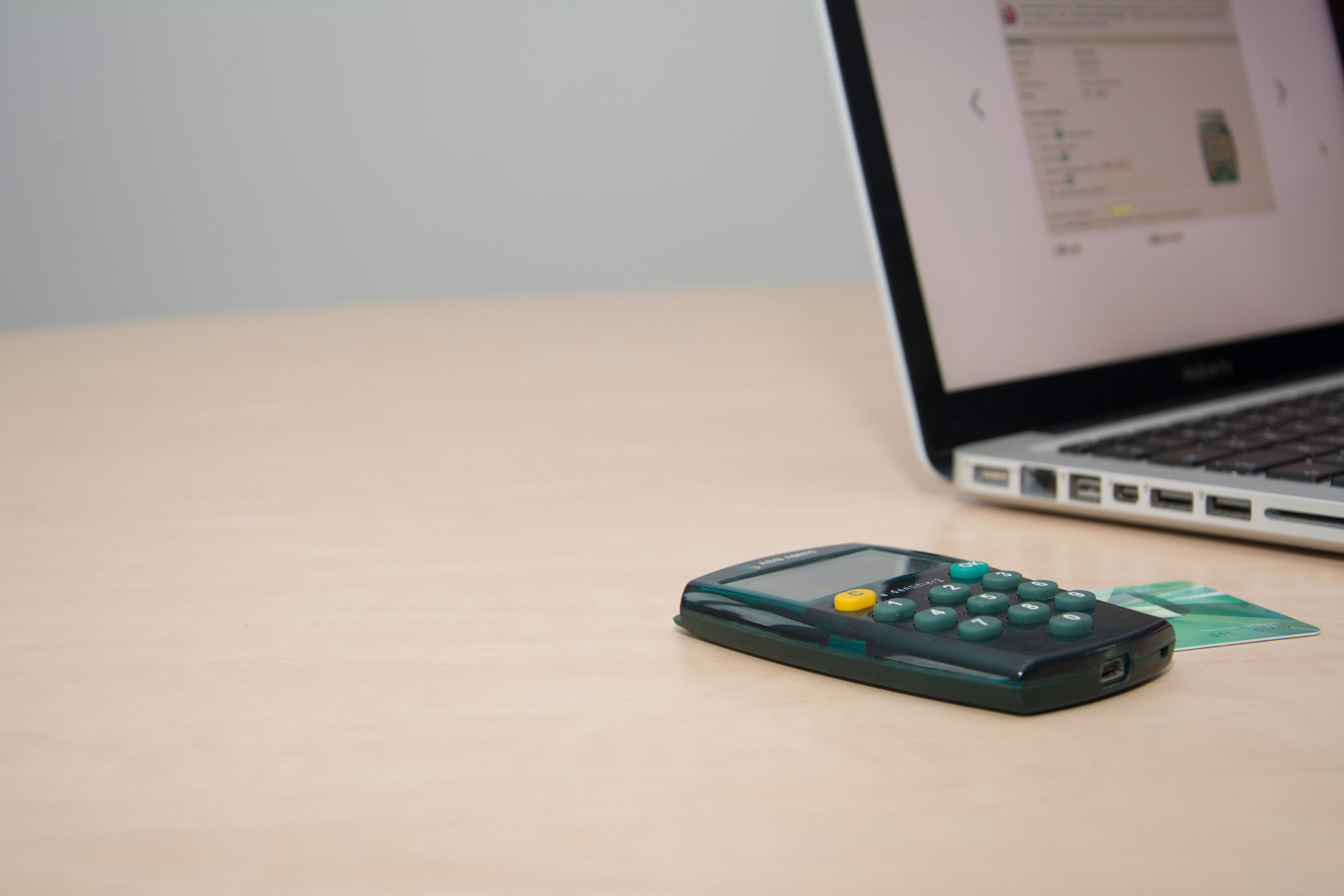 Credit card beside a calculator and laptop on a desk for managing personal finances.
